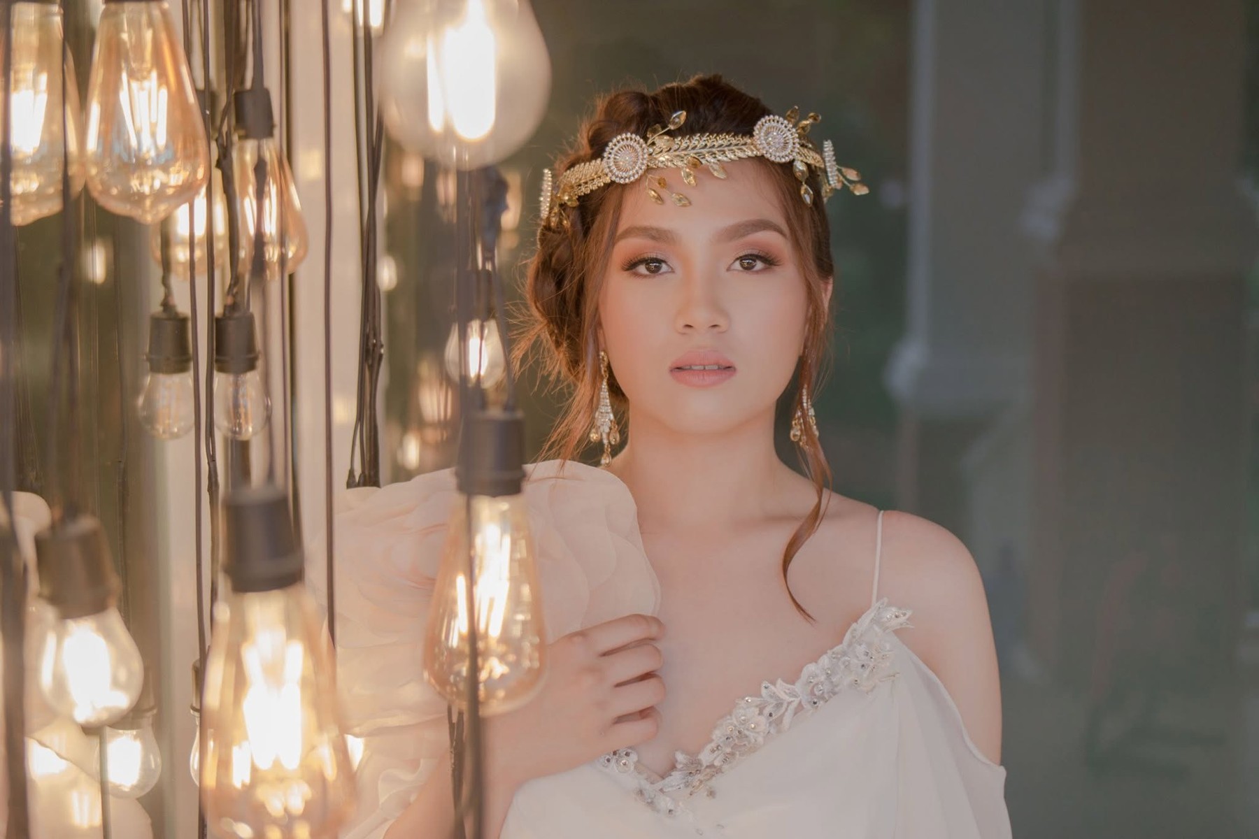 Sophia in an ivory gown surrounded by warm hanging lights